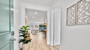 Un pasillo con piso de madera que conduce a una sala de estar con sofá y mesa de comedor.