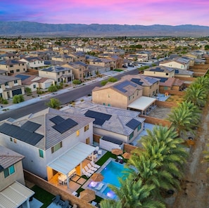 A residential area with modern houses, a swimming pool, and a view of distant mountains.