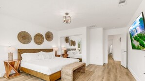 Un dormitorio amplio con una cama grande, cabecera de madera y un televisor de pantalla plana en la pared.