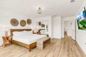 Ein geräumiges Schlafzimmer mit einem großen Bett, einem Holzkopfstück und einem Flachbildfernseher an der Wand.