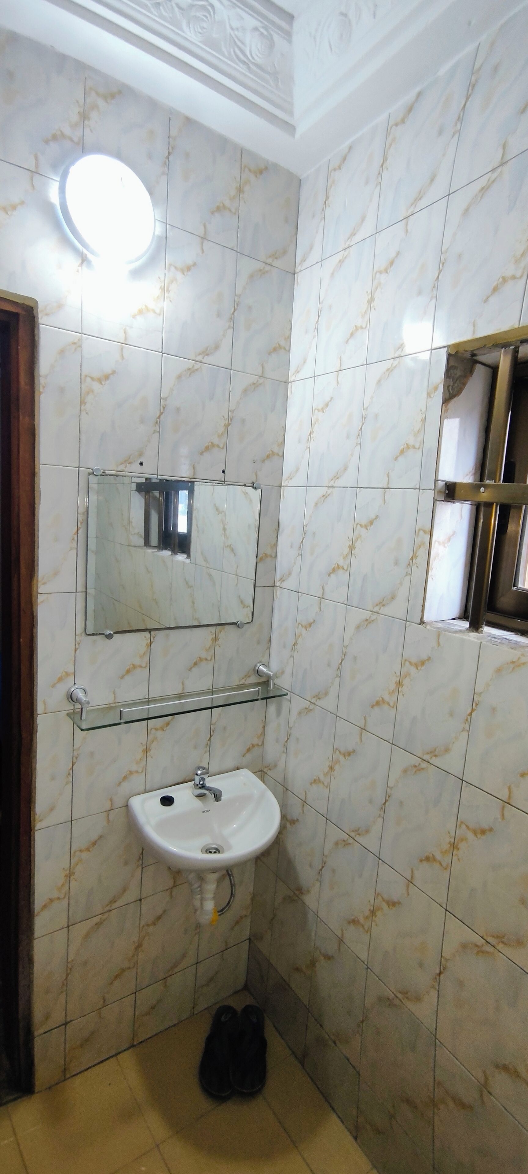 Une salle de bain avec un lavabo blanc, un miroir et une étagère en verre.