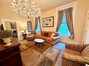 A living room with a chandelier, a sofa, a coffee table, and a patterned rug.