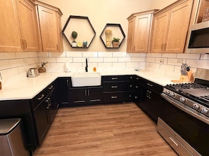 A kitchen with wooden cabinets, a white countertop, a stainless steel stove, and a white sink.