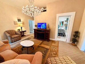 A living room with a fireplace, a television, and a chandelier.