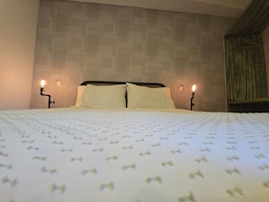 Ein Hotelzimmer mit einem großen Bett, zwei Nachttischlampen und einem Holzkopfteil.