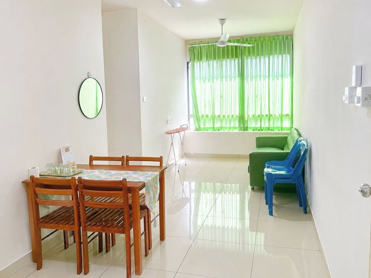 A dining area with a table and chairs, a green sofa, and a window with curtains.. JAA Homes KK, Location: UCA1 KK, Sleeps 8 Near UMS, 1Borneo & Kota Kinabalu City