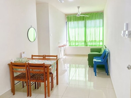 A dining area with a table and chairs, a green sofa, and a window with curtains.. JAA Homes KK, Location: UCA1 KK, Sleeps 8 Near UMS, 1Borneo & Kota Kinabalu City