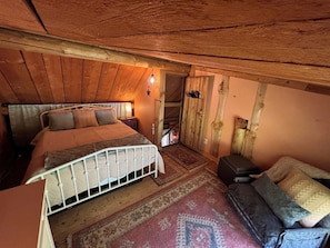 Ein gemütliches Schlafzimmer mit Bett, Sofa, Teppich und Holzwänden.
