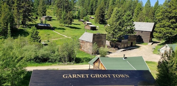 A rustic log cabin area named Garnet Ghost Town with multiple wooden buildings and a dirt path.