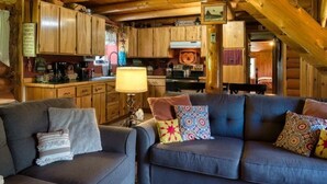 Interior d'una cabana de fusta amb saló, cuina i menjador.