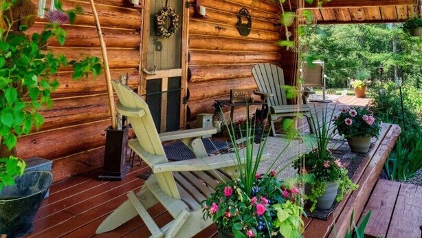 Una cabana de fusta amb un porxo, seients exteriors i jardineres penjants de flors.