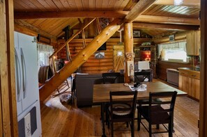 A wooden cabin interior with a dining area, kitchen, and staircase. -  Montana’s Hidden Mile: Forest Trails, River Days, and Star‑Filled Nights (Alberton)