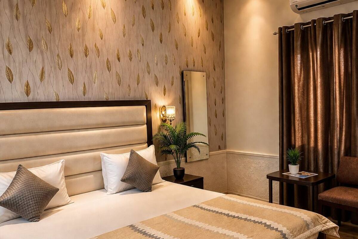 A modern bedroom with a large bed, a nightstand, a mirror, a potted plant, and a chair.