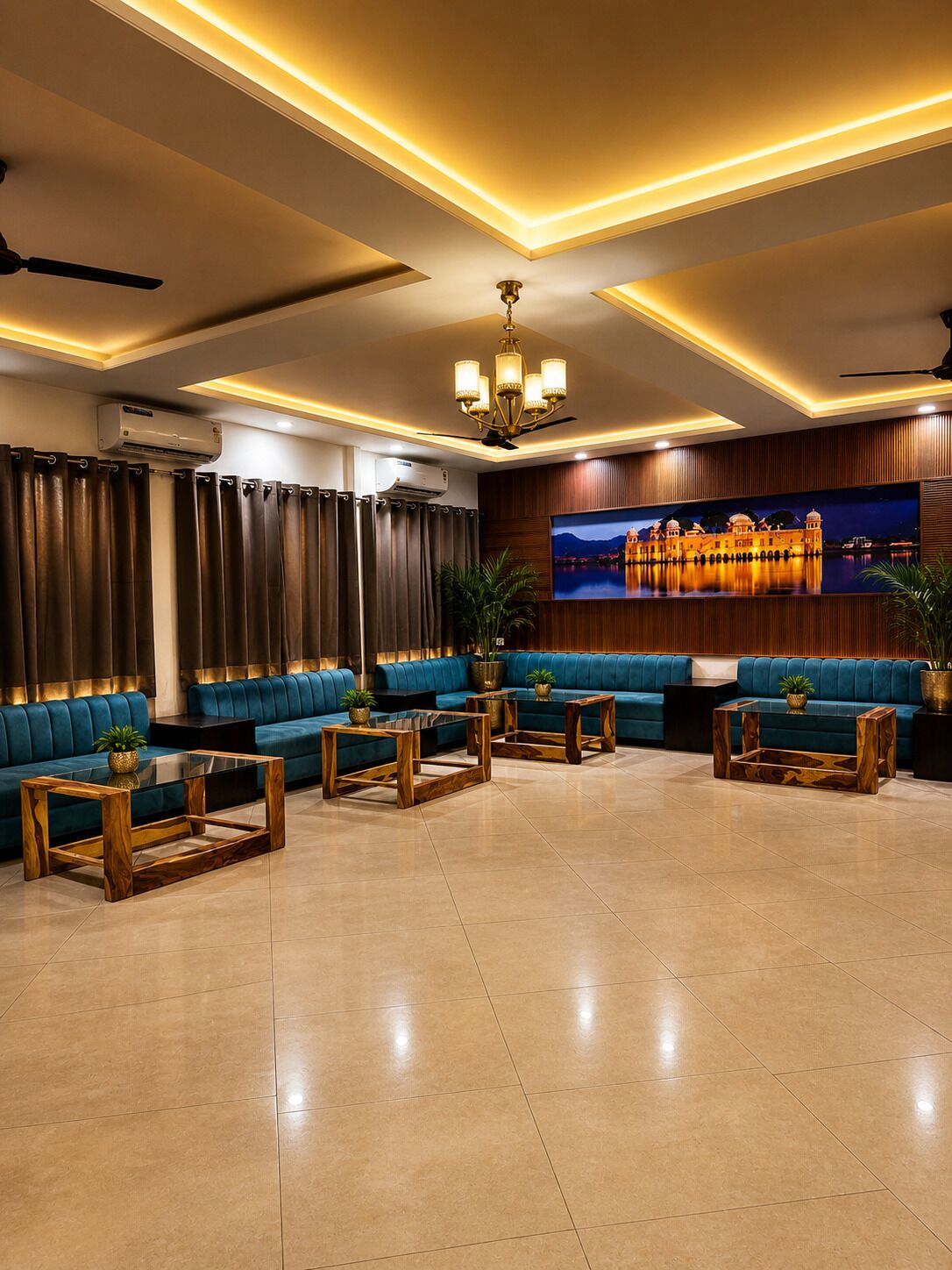 Um hall amplo com área de estar espaçosa, um candelabro e uma grande TV fixada na parede exibindo uma paisagem.