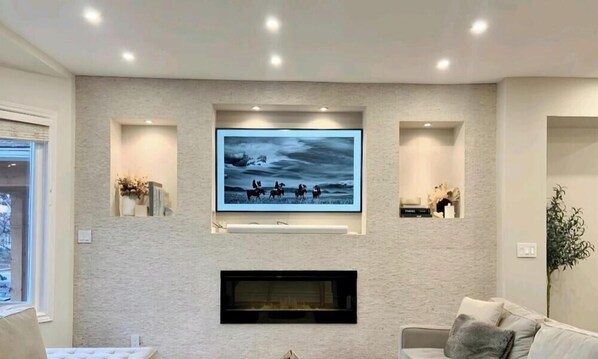 A living room with a mounted TV, built-in shelves, a fireplace, and a couch.