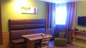 A room with a sofa, a wooden table, a chair, a small ottoman, a television, and a window with curtains. - Apart Bellezza, (Samnaun-Dorf) by Interhome (Samnaun)