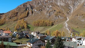 Un villaggio montano con edifici tradizionali, una strada tortuosa e una montagna imponente sullo sfondo.