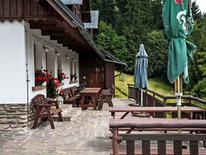 A wooden building with stone walls, outdoor seating, and a green umbrella. - Penzion Exnar by Interhome (Strážné)