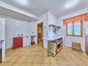 A kitchen with white tiles, a red fridge, a dishwasher, a window with a checkered valance, and a radiator. - Penzion Exnar by Interhome (Strážné)