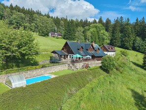 A hillside house with a swimming pool, stone walls, and a forested backdrop. - Penzion Exnar by Interhome (Strážné)