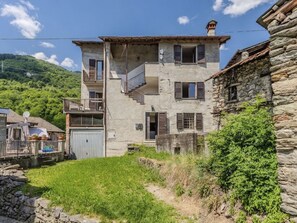 Ein zweistöckiges Steinhaus mit Balkon, kleinem Garten und Steinmauer.