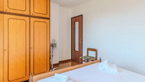 Una camera d'hotel con un letto, una sedia, un armadio in legno e una porta.
