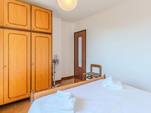 Ein Hotelzimmer mit einem Bett, einem Sessel, einem Holzschrank und einer Tür.