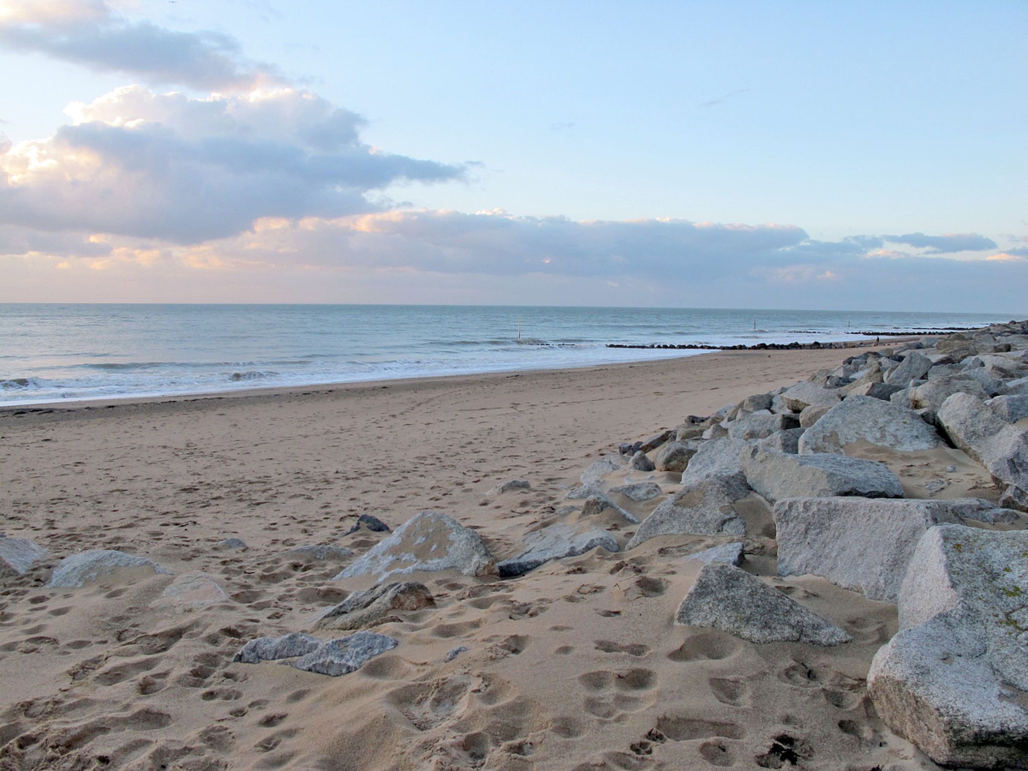 Une plage avec de gros rochers au premier plan et une mer calme à l’arrière-plan.