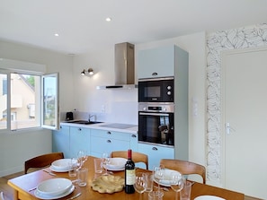 A modern kitchen with a Bosch oven and a dining area set for a meal. - Dolce Vita by Interhome (Agon-Coutainville)
