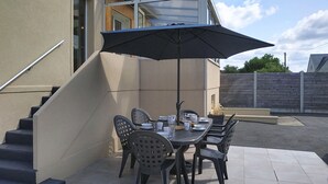 A patio with a table and chairs, a black umbrella, and a staircase. - Dolce Vita by Interhome (Agon-Coutainville)