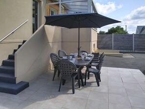 A patio with a table and chairs, a black umbrella, and a staircase. - Dolce Vita by Interhome (Agon-Coutainville)