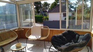 A sunroom with large windows, wicker furniture, and a tiled floor. - Dolce Vita by Interhome (Agon-Coutainville)