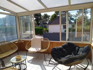 A sunroom with large windows, wicker furniture, and a tiled floor. - Dolce Vita by Interhome (Agon-Coutainville)