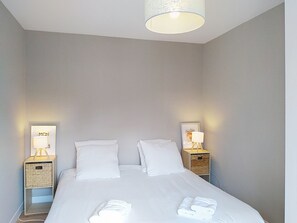Ett hotellrum med en säng, två sängbord, en lampa på varje bord och en inramad tavla på en av väggarna.