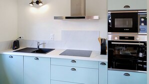 A modern kitchen with a Bosch microwave, oven, and a built-in range hood. - Dolce Vita by Interhome (Agon-Coutainville)