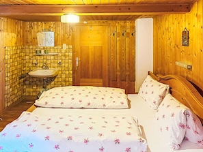 Ein Zimmer aus Holz mit einem Bett, einem Waschbecken und einer Tür.