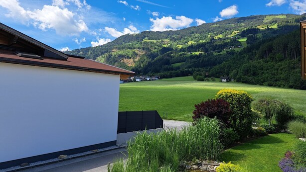 Ein Wohngebiet mit einem weißen Gebäude, grünen Feldern und einem Berg im Hintergrund.