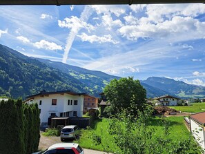 Ein Wohngebiet mit Häusern, einem Auto und Bergen im Hintergrund.