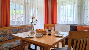 Ein Essbereich mit Holztisch, Stühlen, einer Blumenvase und einem Brotkorb.