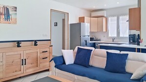 Uma sala de estar moderna com um sofá, um armário de madeira e uma cozinha com armários e uma geladeira.