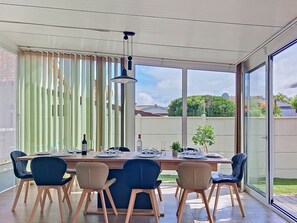 Ein Essbereich mit Tisch für vier Personen, großen Fenstern und Blick auf den Garten.
