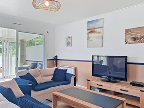 Ein modernes Wohnzimmer mit Sofa, Couchtisch, Fernseher und Bildern an der Wand.