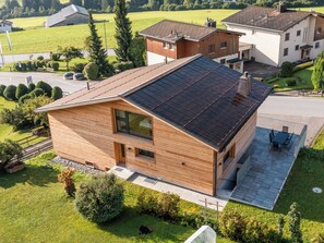 Ein modernes Haus mit Satteldach, großen Fenstern und einer Terrassenfläche.