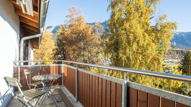 A balcony with a view of autumn trees and mountains.