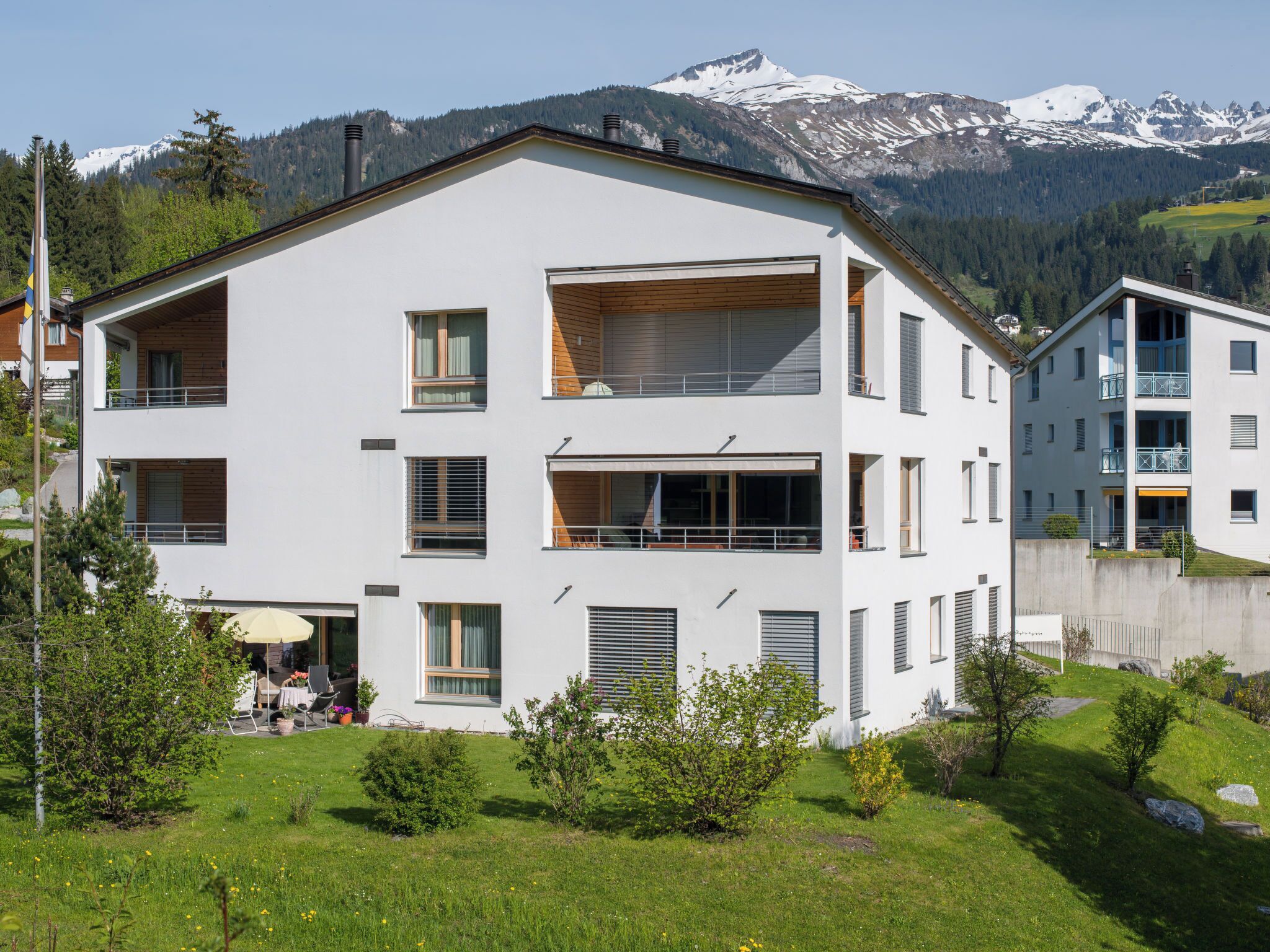 Ein modernes, zweistöckiges Gebäude mit Flachdach, großen Fenstern und einem Balkon.