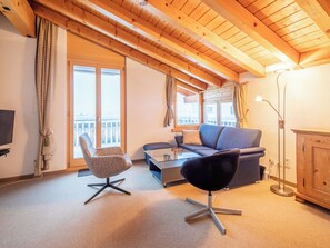 Ein gemütliches Wohnzimmer mit Sofa, Sessel und Fernseher.