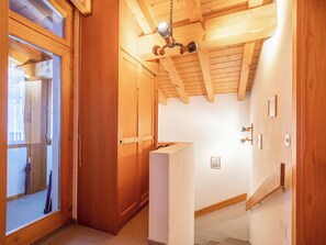 Ein Holzeinrichtung mit Deckenventilator, einer Tür zu einem Zimmer und einem kleinen Regal.