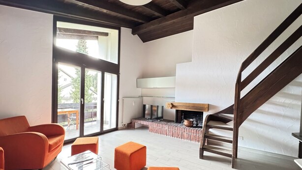 Ein großzügiger Wohnbereich mit Kamin, einer Holztreppe und einer großen Schiebeglastür.