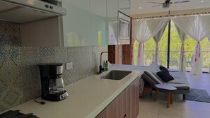 A modern kitchen with a coffee maker, a sink, and patterned tiles. - Spacious study with a view of the pool (Q.R.)