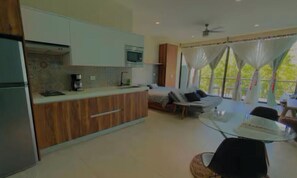 A modern kitchen with a microwave, coffee maker, and wooden cabinets. There is a dining area with a glass table and chairs. - Spacious study with a view of the pool (Q.R.)